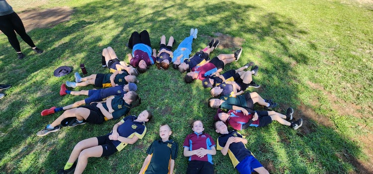 A group of studnets laying in a circle with their heads in the centre